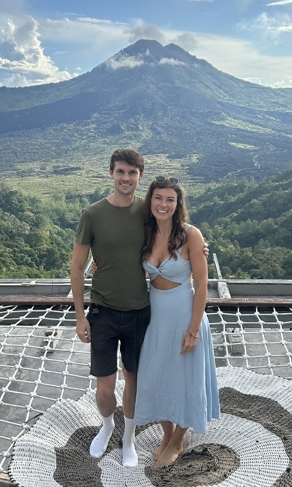 Mike and Pip standing together in front of a volcano and green hills
